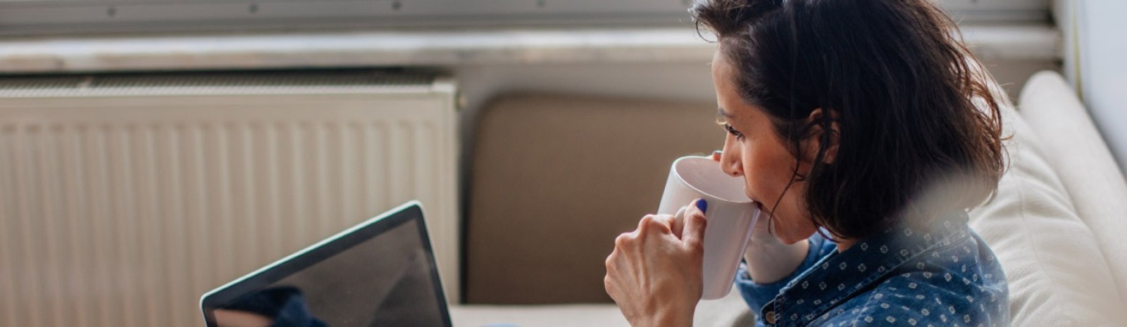 a woman sitting on a couch drinking from a mug