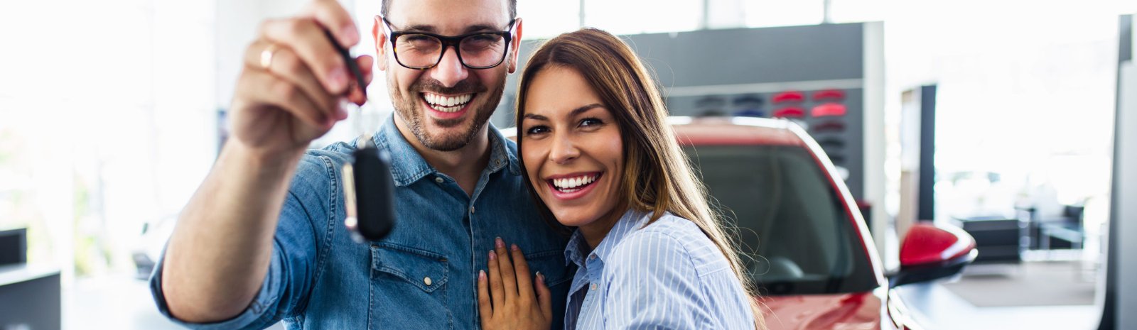 a couple holding the keys to a new car