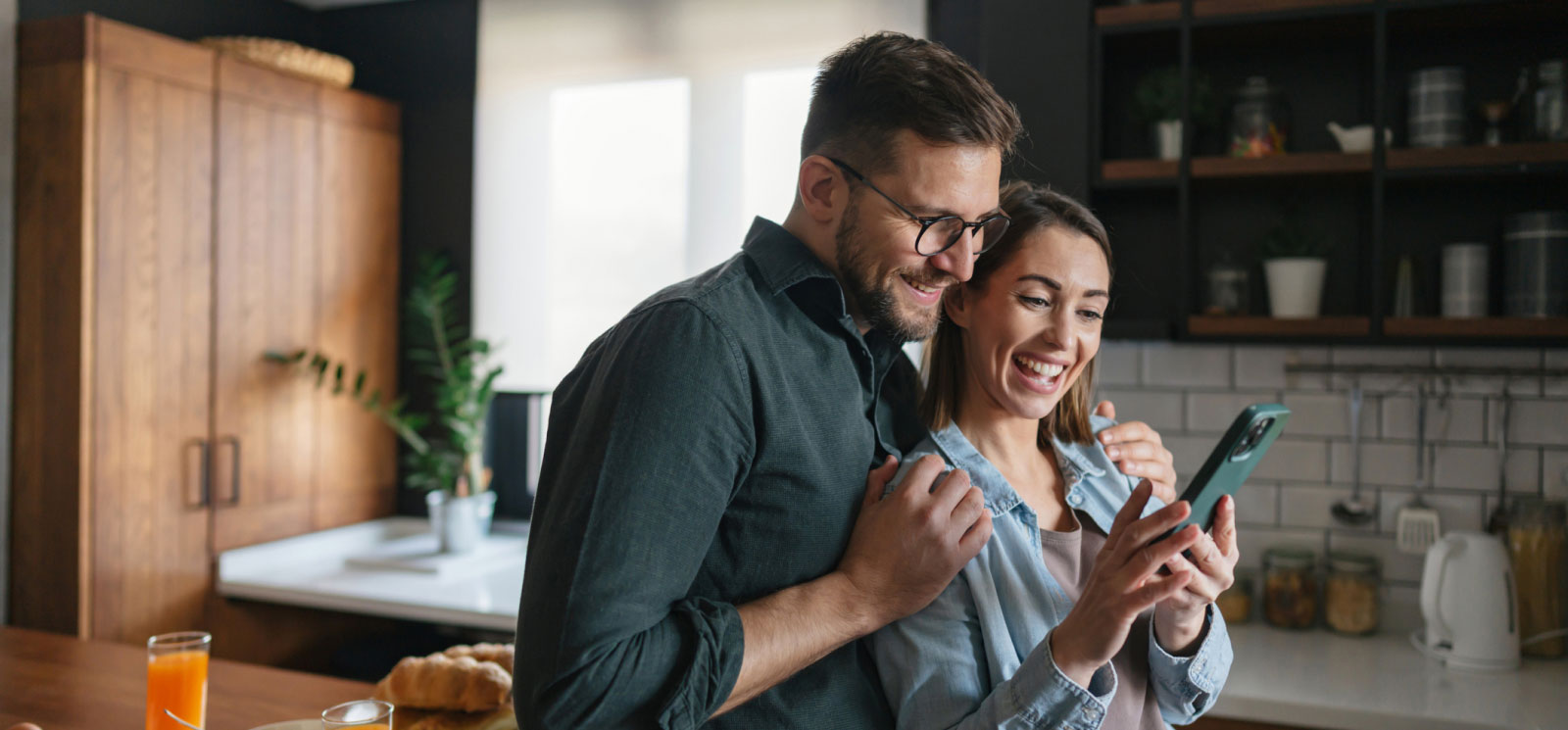 a young couple looking at a smartphone inside a modern kitchen